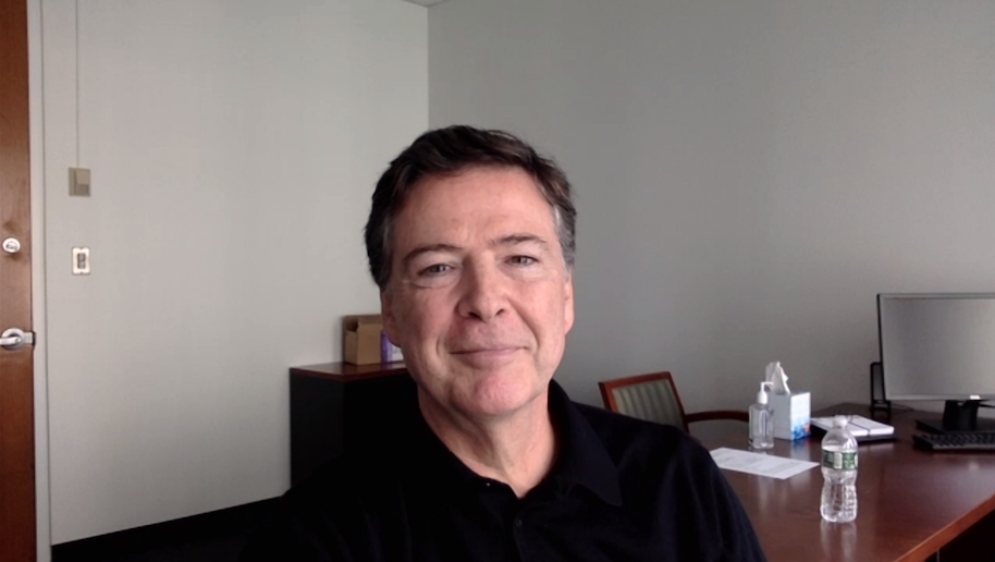 Caucasian male in black shirt (James Comey) sitting in office.